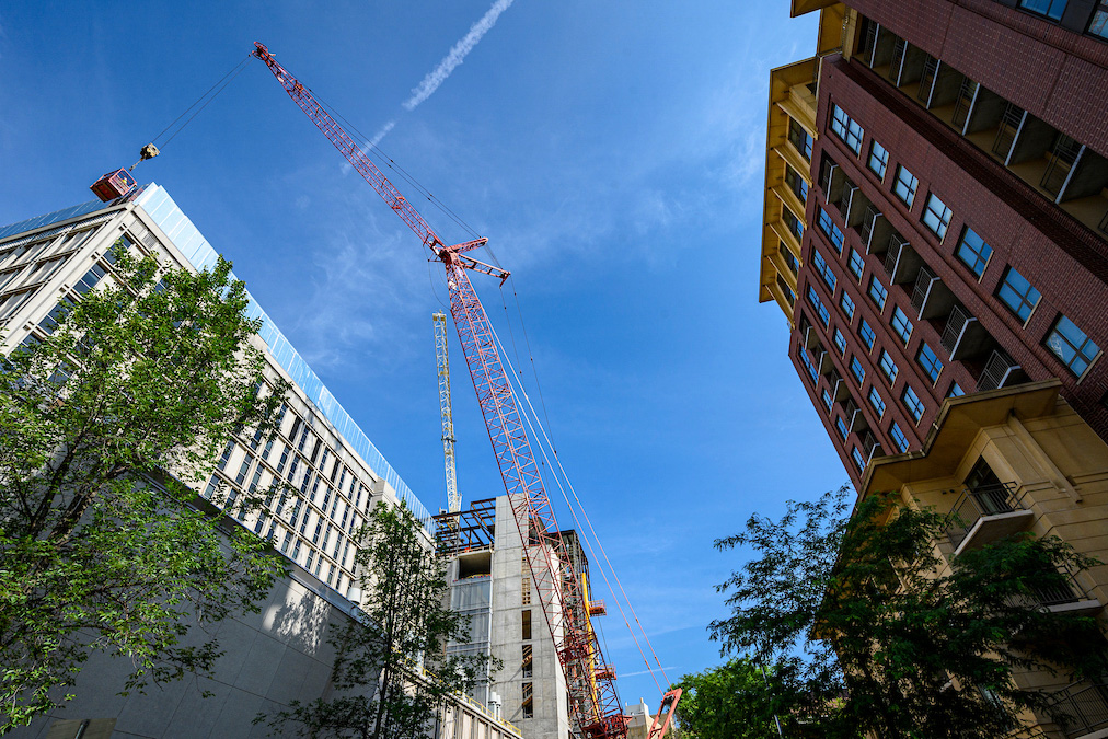 A red construction crane towers above the partially built Chemistry building on campus.
